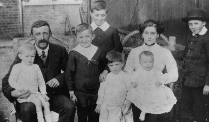 Laurie in sailor outfit with family around 1912-13.