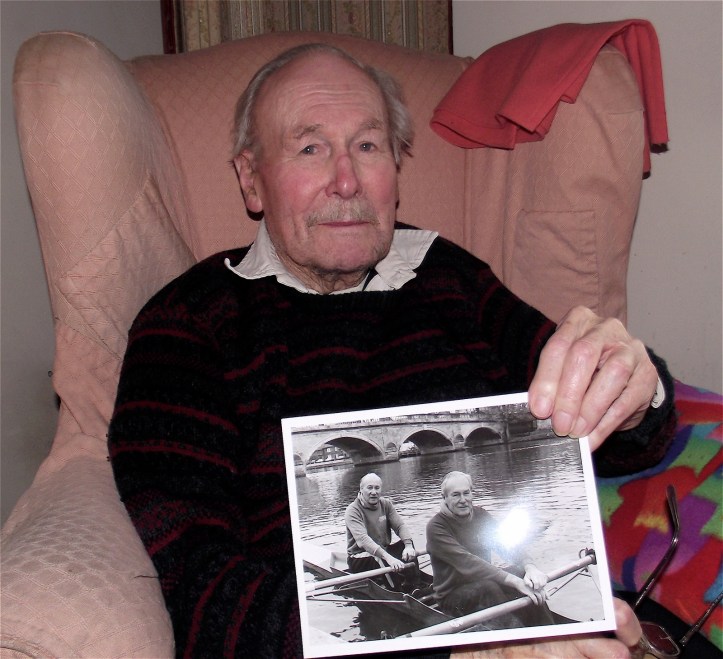 Richard Hylton-Smith photographed in 2013 at the age of 100. He is holding a photograph taken on his 90th birthday in 2002 when he went rowing with his brother Ken, a former secretary of Leander.