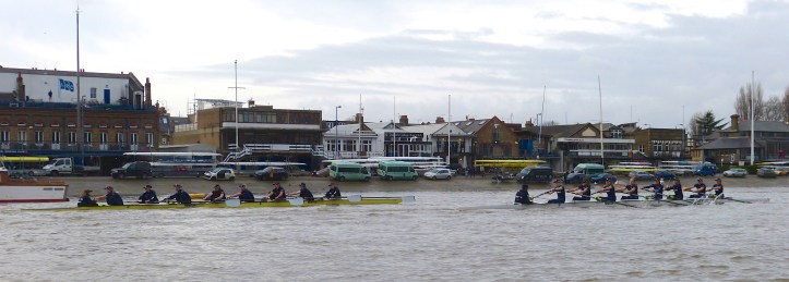 Pic 8. The yellow boat on the Surrey side was stroked by Maddy Badcott and was given the name ‘Charybdis’. The white boat on Middlesex was called ‘Scylla’ and the stroke was Emma Lukasiewiez. The names on the two boats came from a Greek phrase meaning ‘having to choose between two evils’ (something that I intend to drop into conversation in the future). Pictured here passing London Rowing Club, Scylla took an early lead.