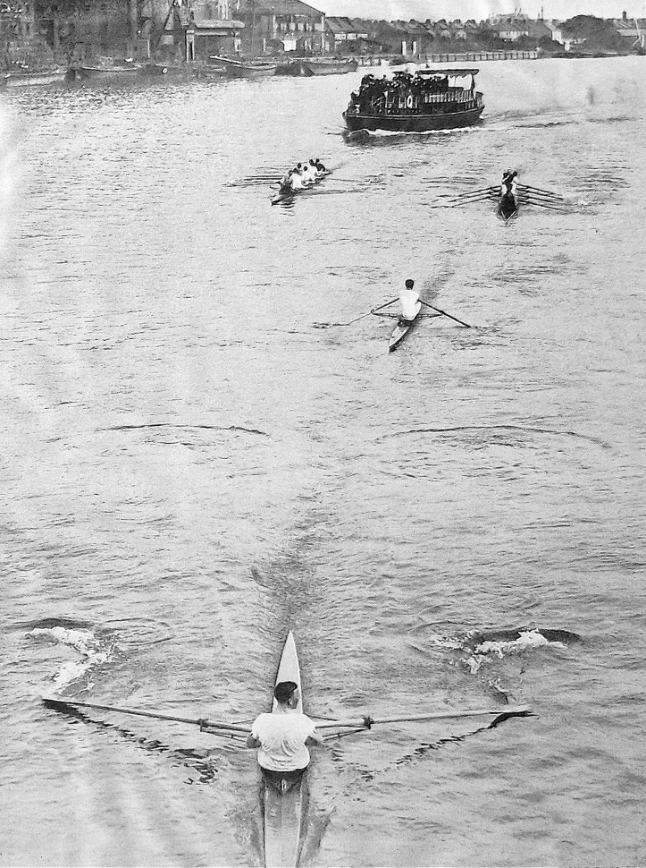 Pic 3. The 1912 Wingfield Sculls. At Hammersmith Bridge, WD Kinnear of Kensington RC leads EDP Pinks of London RC. The bowmen of the following eights are not rowing and are facing the bow, each directing their respective man, something allowed under the race rules then and now (though nowadays it is done from motorboats).