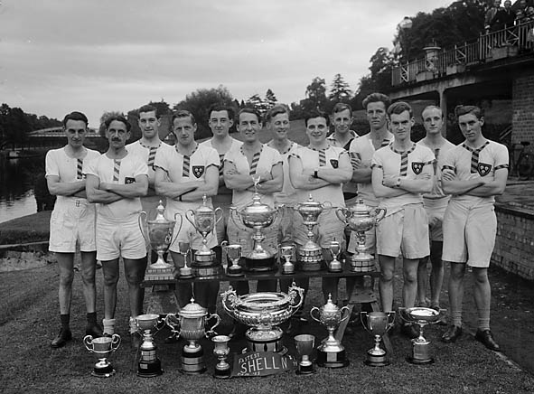 A group portrait of members of Pengwern Boat Club, Shrewsbury, with 18 trophies won during that season, a club record.