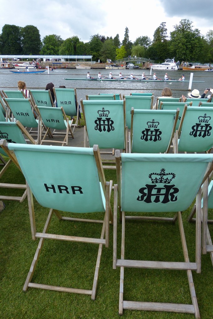 A row past during the tea interval by the Hong Kong and China Rowing Association to mark 40 years since Hong Kong crews first rowed at Henley Royal Regatta. New deck chairs now have the Regatta logo replacing the simple letters ‘HRR’ and this increases their desirability as ‘souvenirs’. There are doubtful legends about individuals dismantling chairs and smuggling them out, one piece at a time. There are also tales of complete chairs being taken out by river.