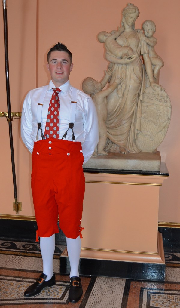 Louis Pettipher, the 2015 winner, gives a rare full sight of the breeches that accompany the more famous Coat. Loose-fitting, high waisted, supported by braces (US: suspenders) and with an elaborate buttoned flap fly arrangement, this is how all men’s trousers were in pre-zipper days when shirts were regarded as underwear and a gentleman would never remove or unbutton his jacket in public.