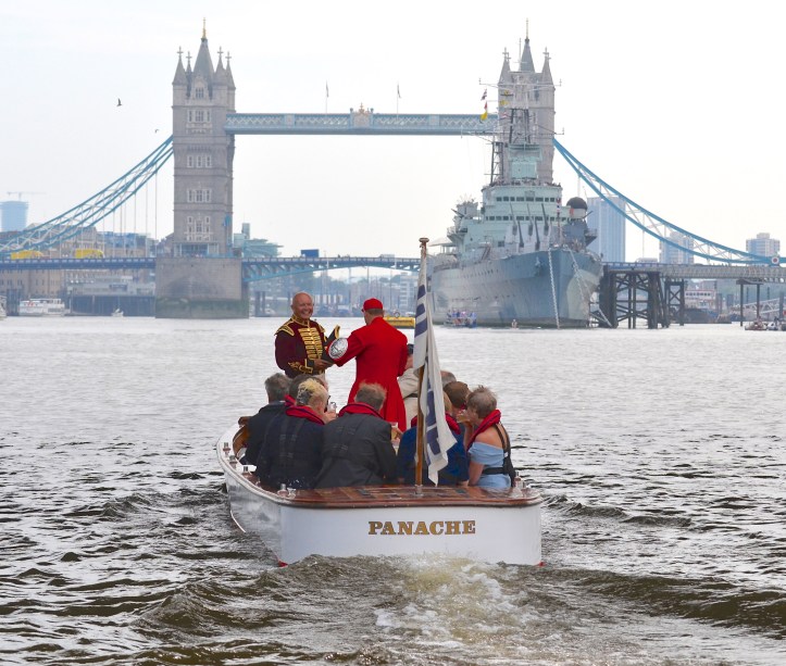 The umpire’s launch heads to the marshalling area around the permanently moored HMS Belfast, just below Tower Bridge. Robert is in the purple and gold of the Fishmongers’ Bargemaster while the man in Doggett’s scarlet is Robert’s old Henley, National Championships and Home International partner, Martin Spencer.