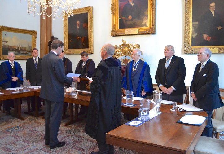 In the Court Room, Daniel Walker takes the oath at the Court of Admission in front of the Master (obscured), his Wardens and the other officers.