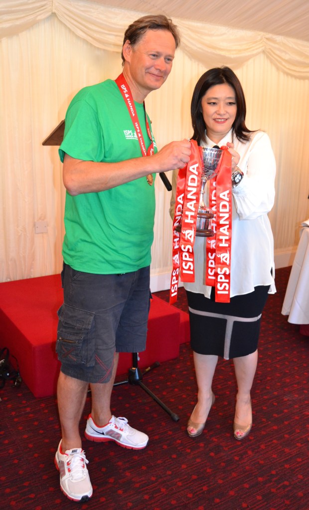The leader of the victorious Commons team, Dr Matthew Offord MP, accepts the race trophy from Midori Miyazaki, a representative of Dr Haruhisa Handa, Chairman of the International Sports Promotion Society, sponsor of the Parliamentary Boat Race.