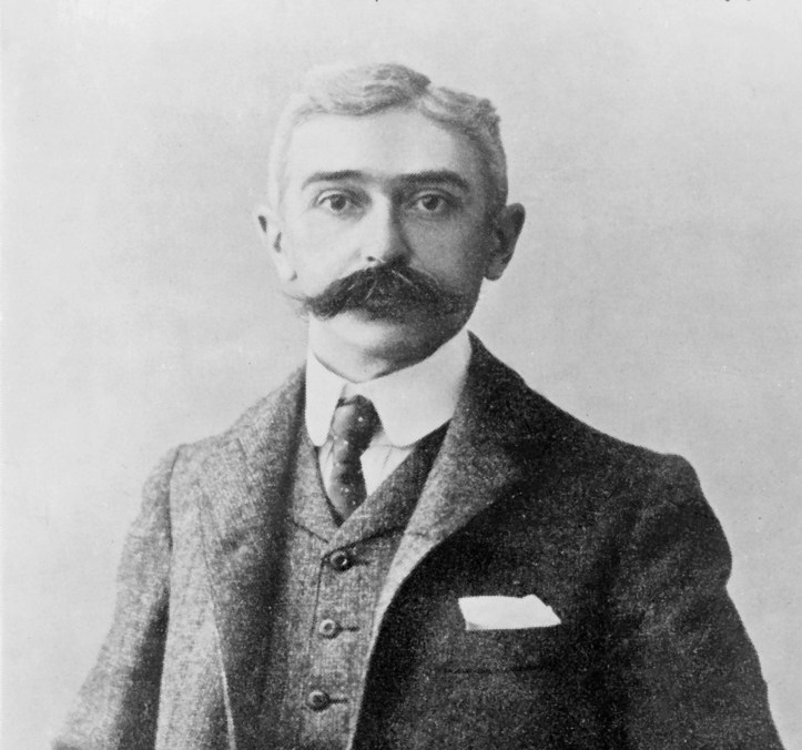 Baron Pierre de Coubertin, keen sculler and founder of the modern Olympic Movement, possibly holding a small dog under his nose.