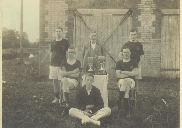 Stars of the County Down – A coxed four and coach pictured outside the club’s boathouse on the Newry Canal. Rowers named as H. J. McConville, Joseph Fisher, Joe Dunlop and W. A. Magowan. The coach could be the same person pictured at five seat in the previous photograph who in turn may be G. T. Allen.