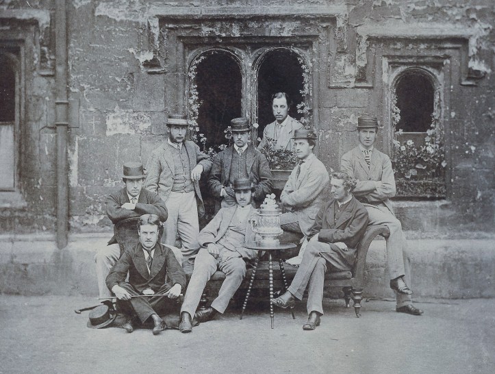 The 1867 Brasenose Head of the River Eight. Woodgate is seated on the right contemplating the trophy.